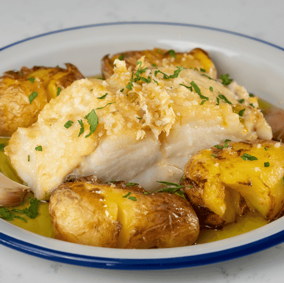 Bacalhau à Lagareiro Tradicional, assado no forno com batatas a murro e azeite, numa travessa de barro