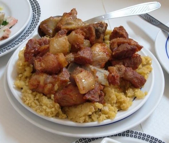 Migas à Alentejana douradas e soltas, servidas numa panela de ferro, acompanhadas de azeitonas