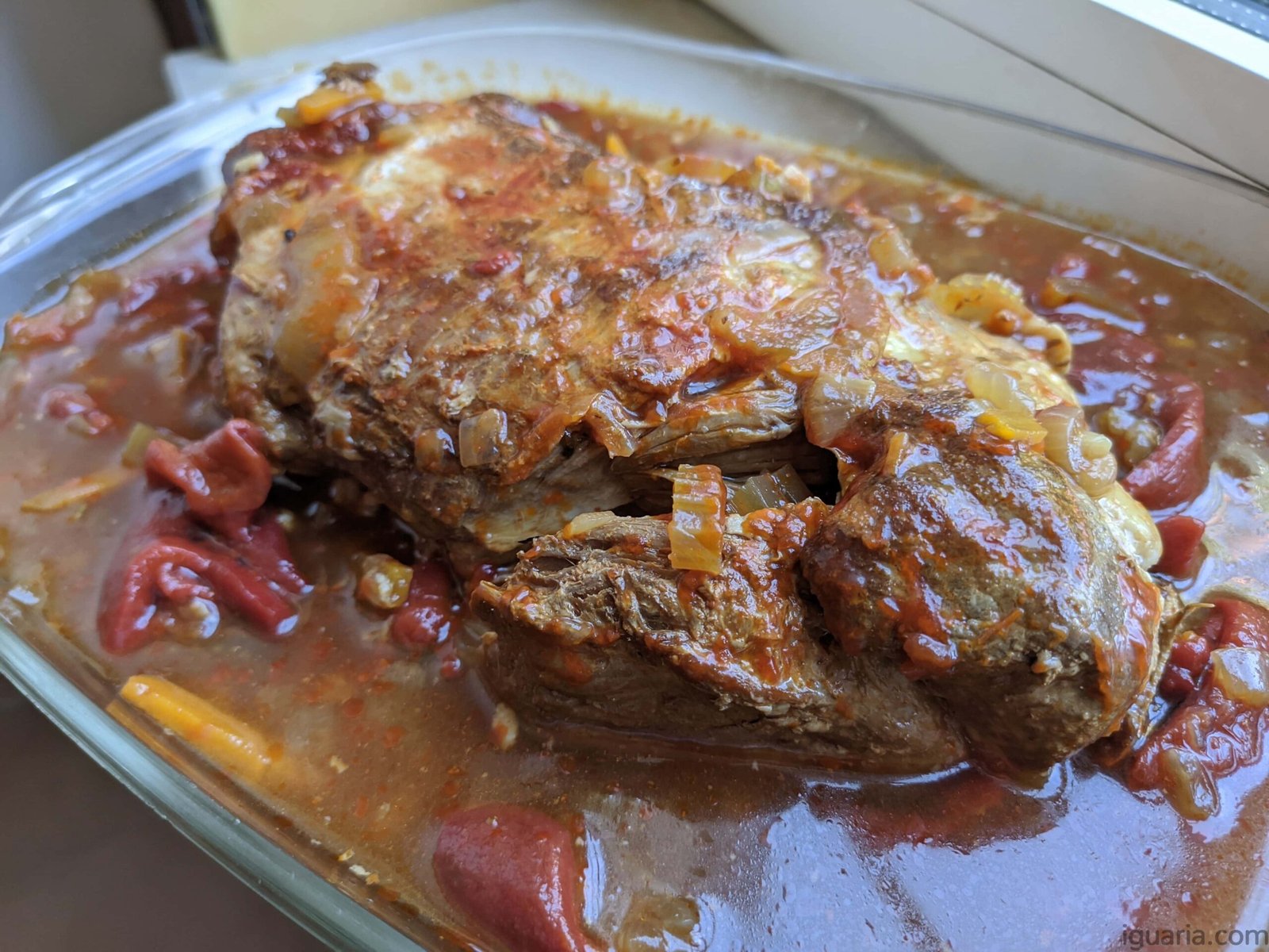 Pé de Porco com Molho Madeira, servido em prato branco com molho escuro e acompanhado de puré de batata