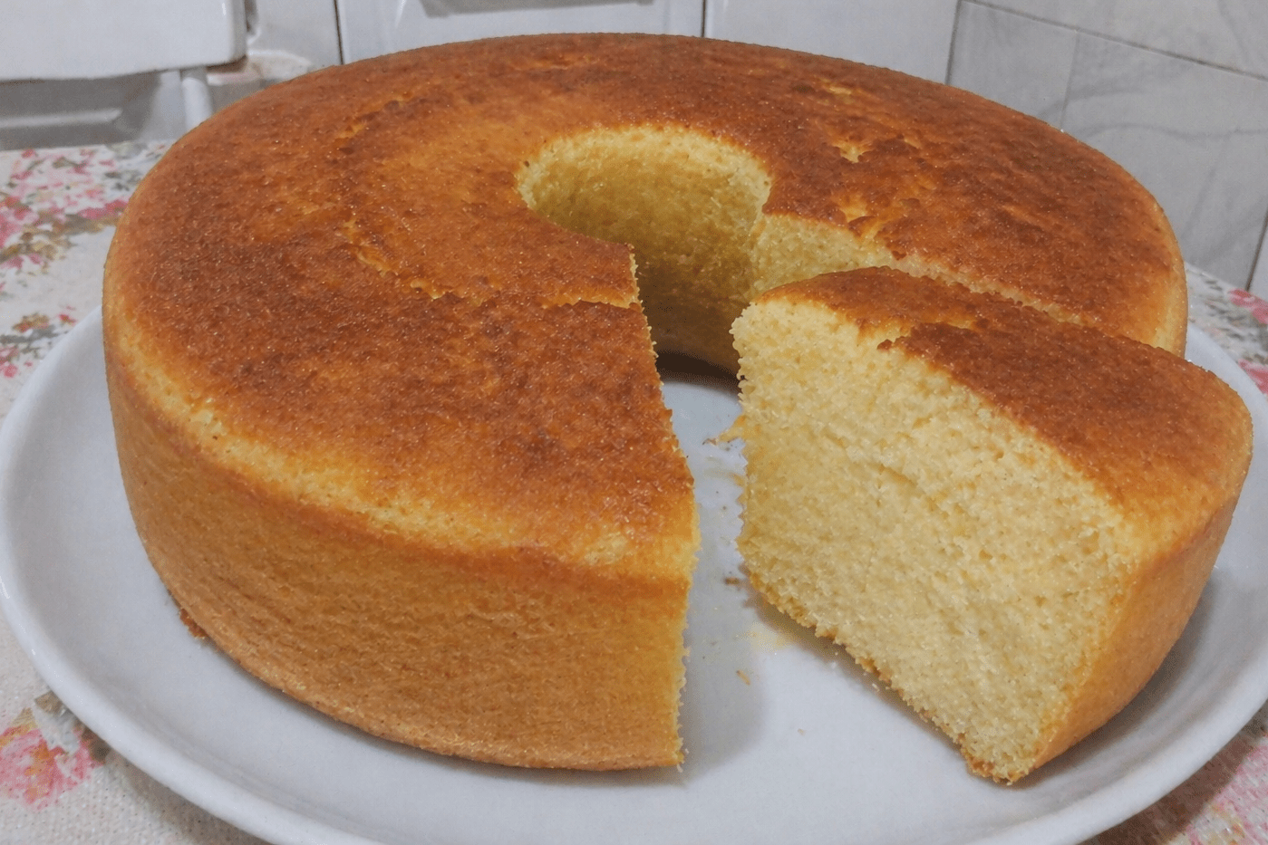 Bolo de leite quente alto, dourado e fofinho em cima de um prato branco com café ao lado