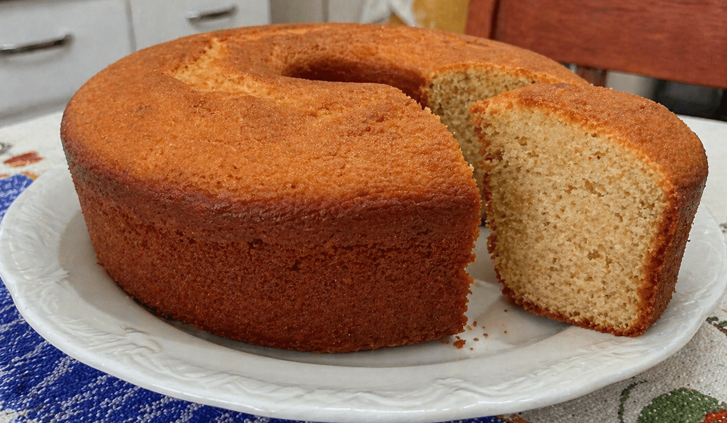 Bolo caseiro dourado e fofinho fatiado sobre uma mesa de café