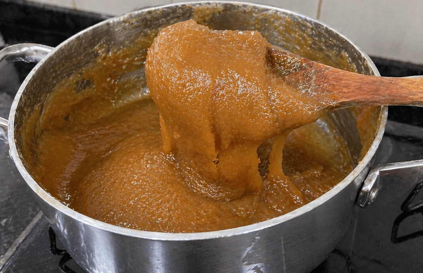 Doce de leite caseiro cremoso em uma colher saindo da panela