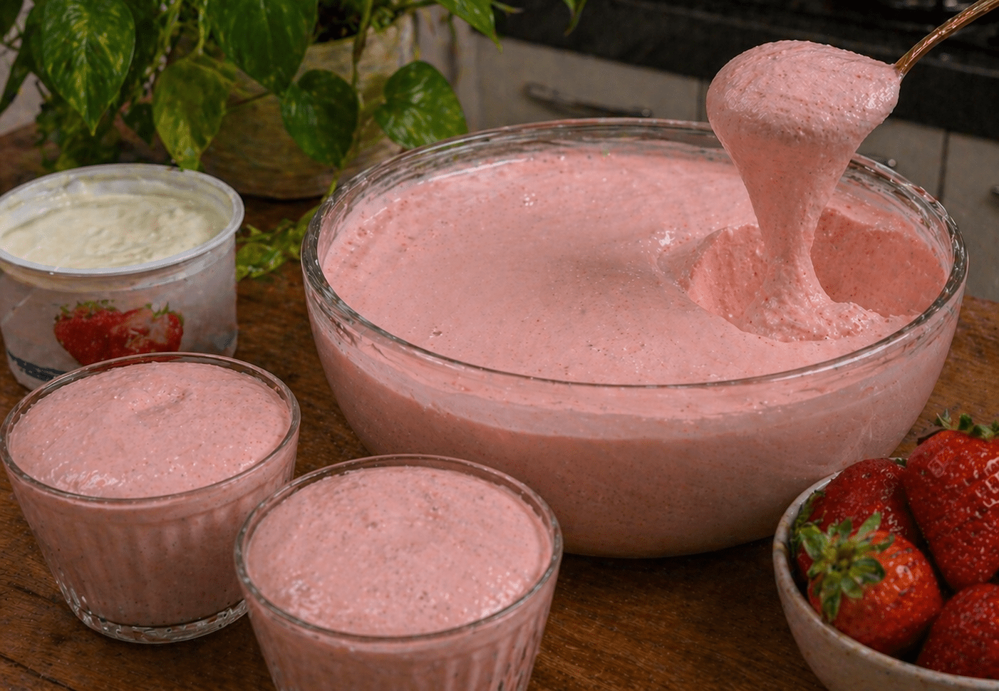 Taça de vidro com mousse de morango rosa decorada com um morango fresco no topo