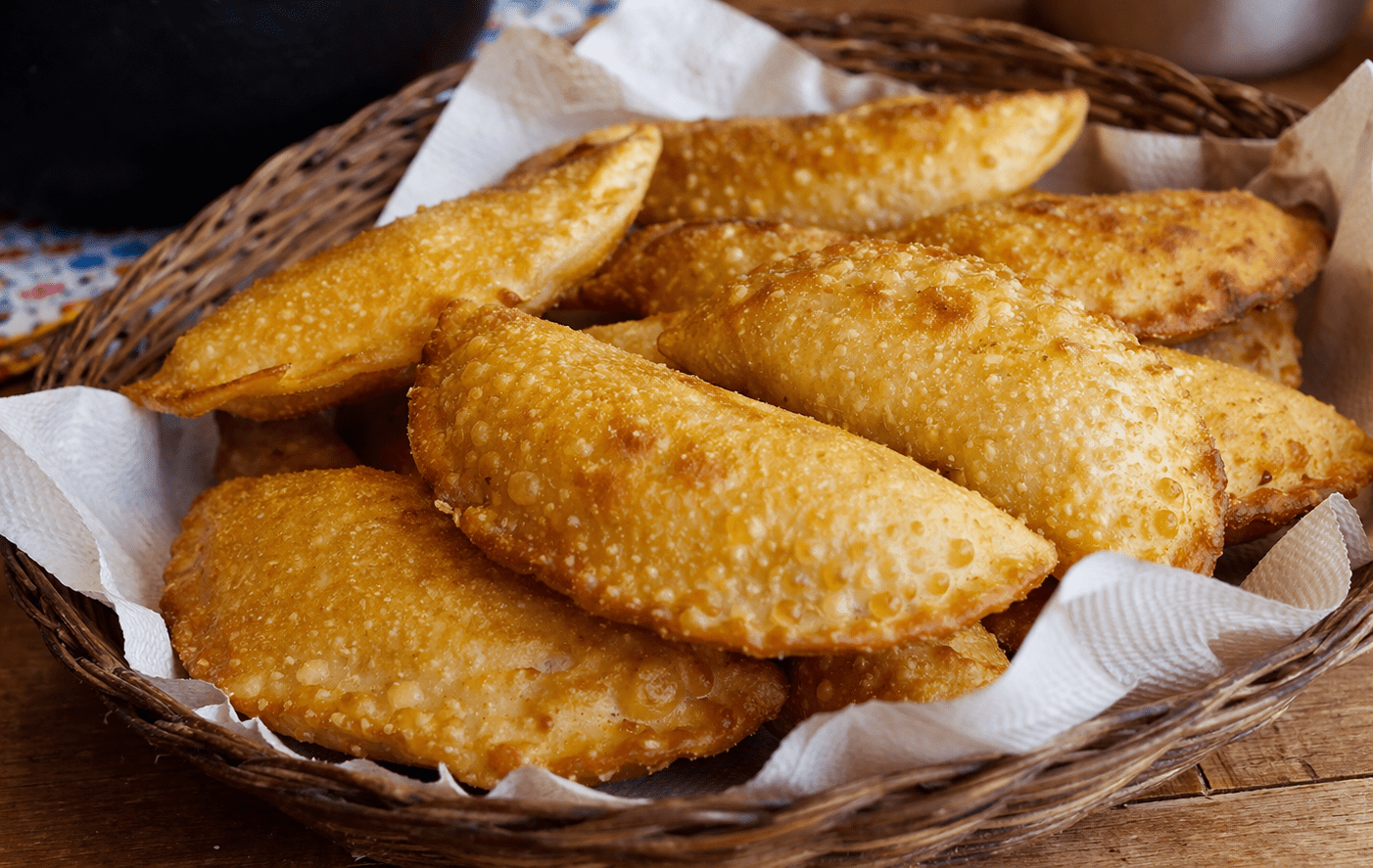 Pastéis de angu dourados e crocantes servidos em uma cesta de vime