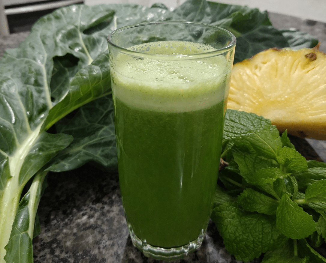 Copo de suco verde detox com fatias de abacaxi, folhas de couve e hortelã fresca