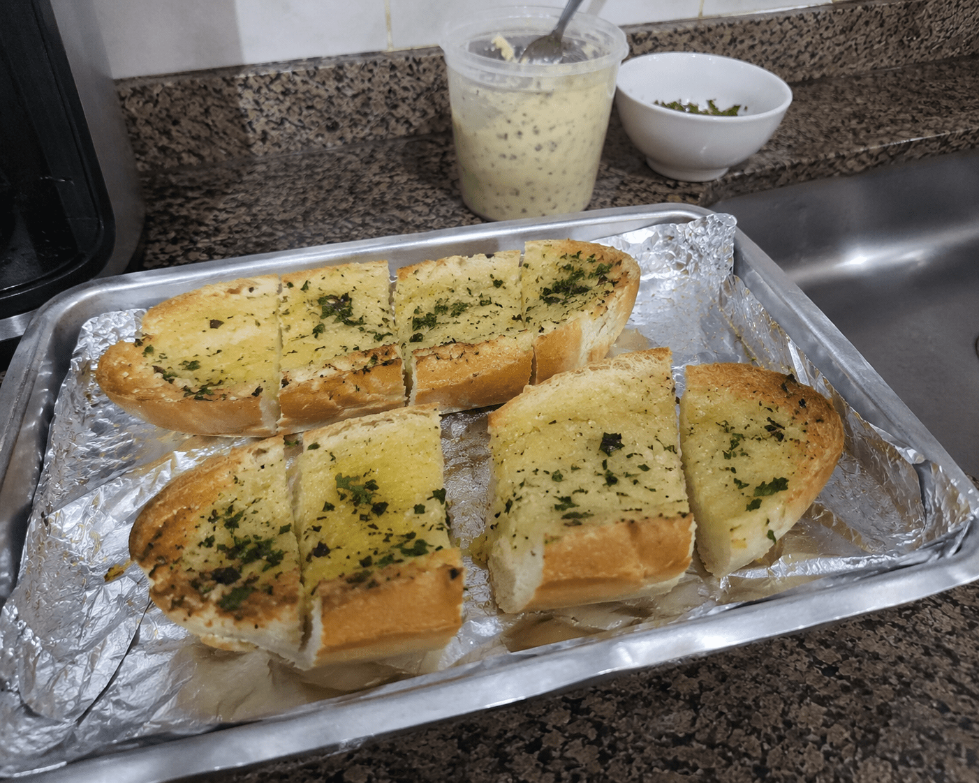 Pães de alho recheados e dourados saindo da grelha com queijo derretido e tempero verde por cima