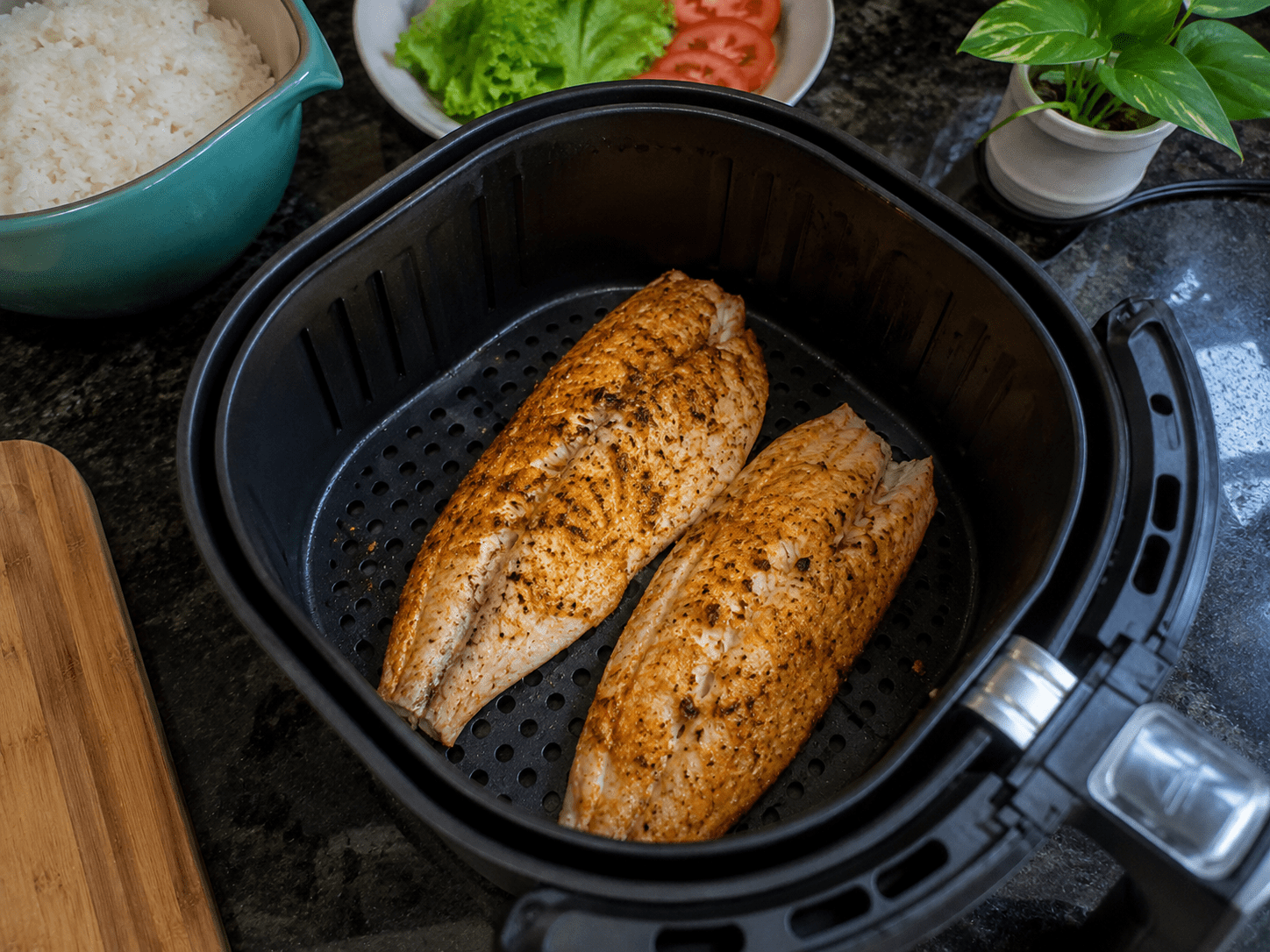 Filés de peixe dourados e suculentos feitos na airfryer dispostos sobre uma mesa com fatias de limão