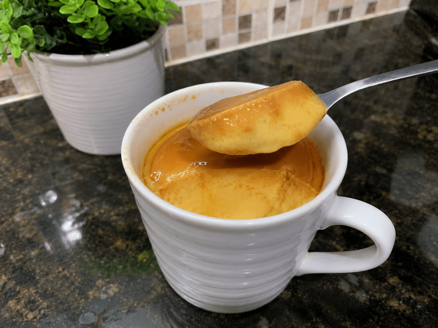 Pudim de caneca individual desenformado em um prato pequeno coberto com calda de caramelo brilhante